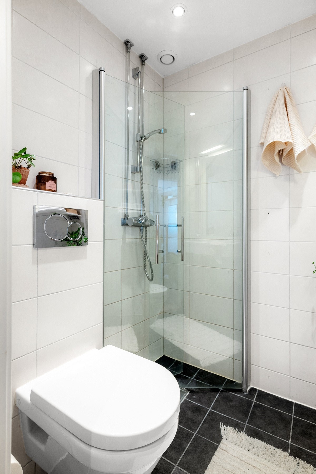 Badet er utstyrt med dusj med innfellbare glassdører, vegghengt toalett og servantskap med ettgreps blandebatteri fra Grohe. Galleribilde