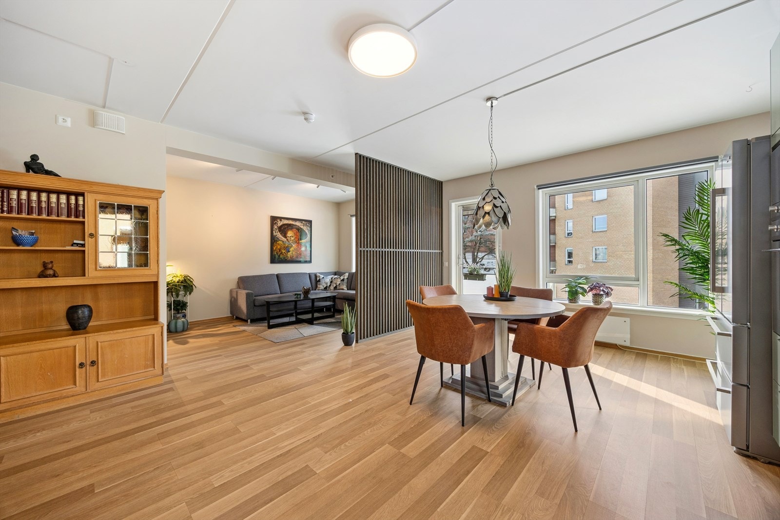 Stuen har en dekorativ spilevegg som gir rommet et moderne uttrykk og skaper en naturlig og luftig avgrensning mot kjøkkenet, uten å bryte den åpne løsningen. Galleribilde