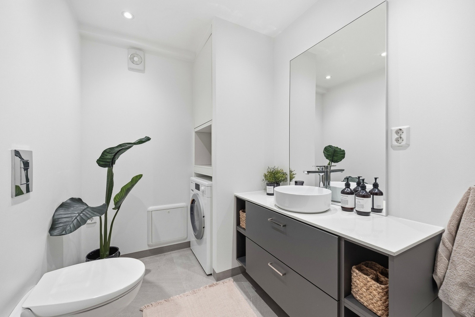 Stilrent baderom med pene fliser og våtromsplater, nytt i 2021/22. Badet er utstyrt med vegghengt toalett, dusjhjørne med vegger og opplegg for vaskemaskin. Galleribilde