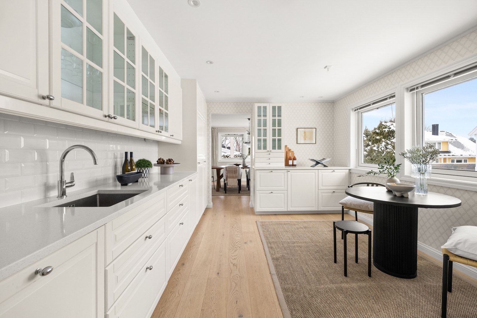 Klassisk og tidløst kjøkkeninnredning, nytt fra 2020. Innredningen har profilerte fronter, hvite fliser på vegg mellom benk og overskap samt benkeplater i lys kompositt. Galleribilde