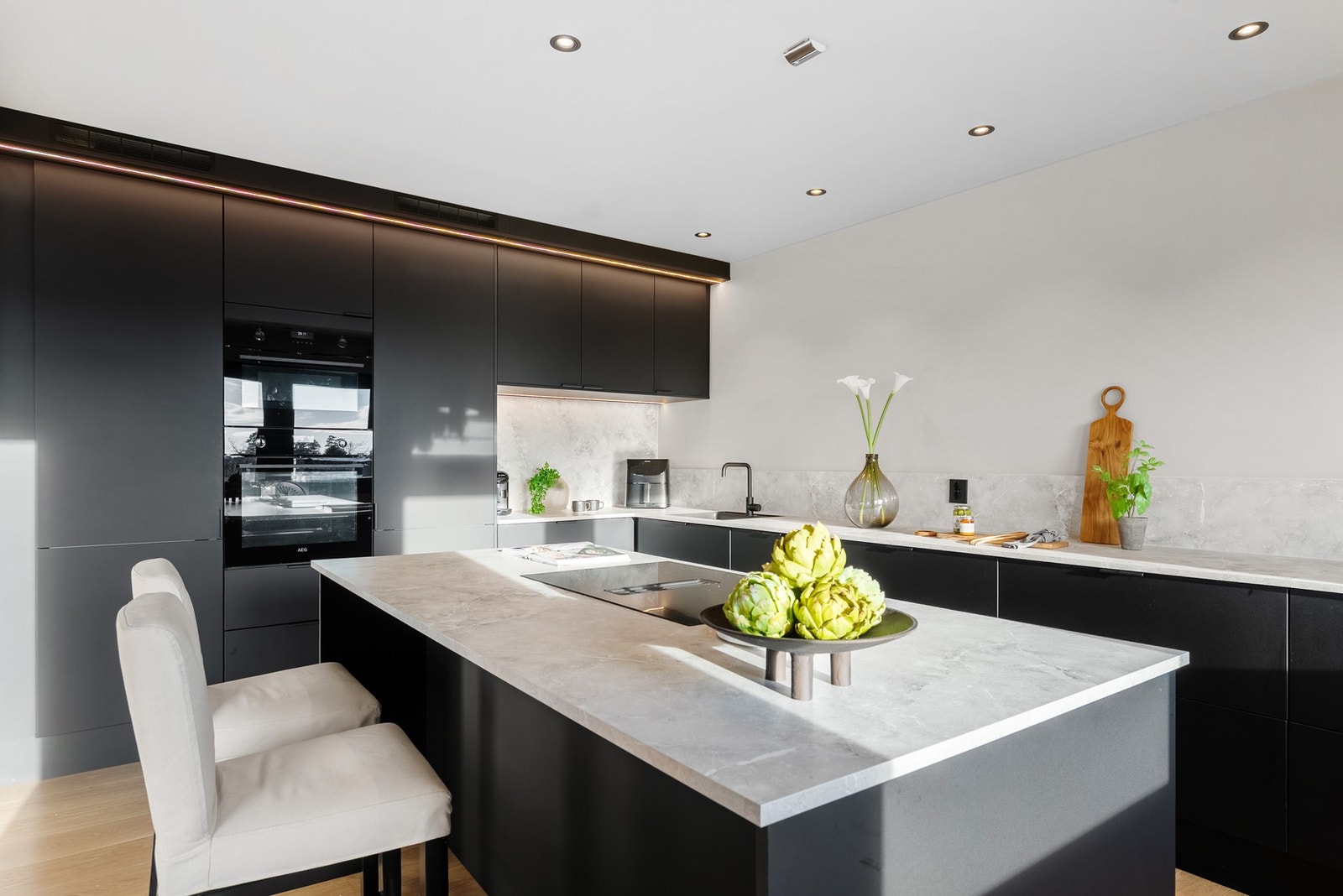 På kjøkkenet har du moderne mørk innredning med slette fronter og elegant benkeplate Galleribilde