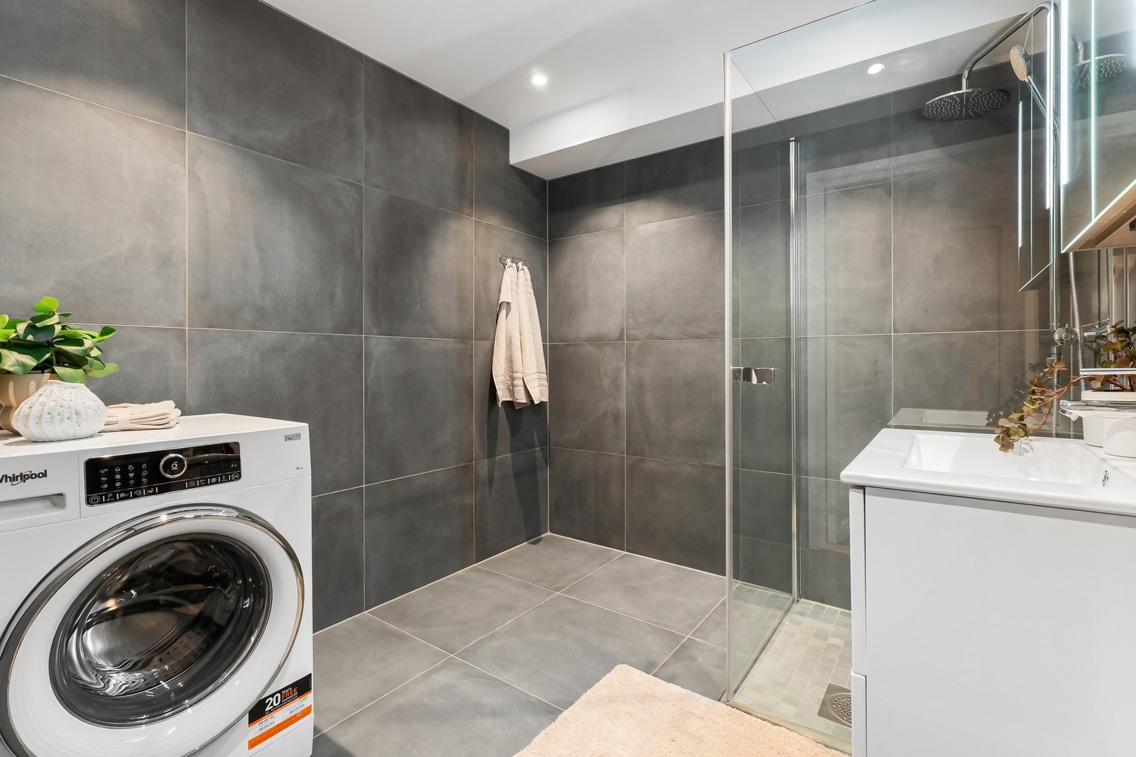 Moderne flislagt baderom med varmekabler i gulv og opplegg for vaskemaskin Galleribilde