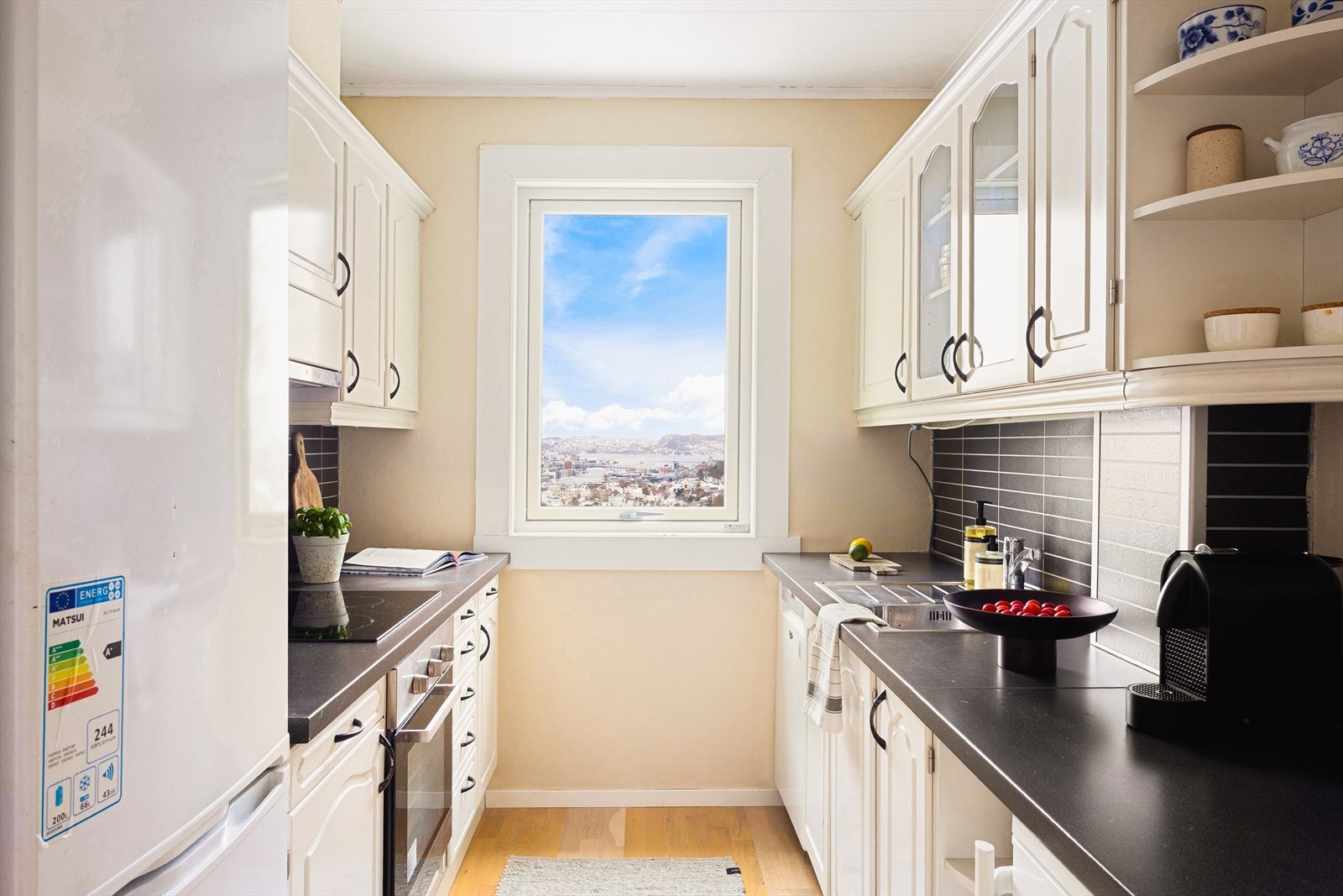 Kjøkkenet finner sin velegnede plass i hjørnet av boligen og er på 8 m². Her finner du et lyst kjøkken innredet med profilerte hvite fronter og to glassfronter. Galleribilde