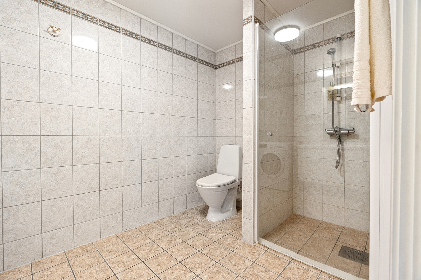 Stort, flislagt bad med god plass for vaskemaskin. Galleribilde