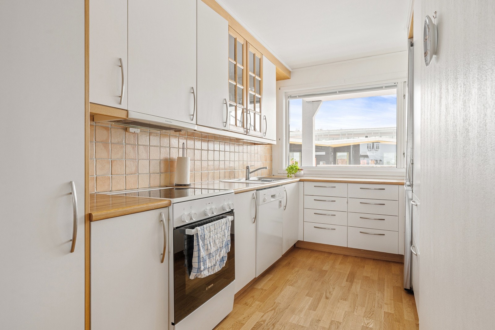 Kjøkken med fliser over stor kjøkkenbenk som sikrer godt med arbeidsplass til kokkeleringen. I tillegg har du godt med oppbevaringsplass i over- og underskap. Galleribilde