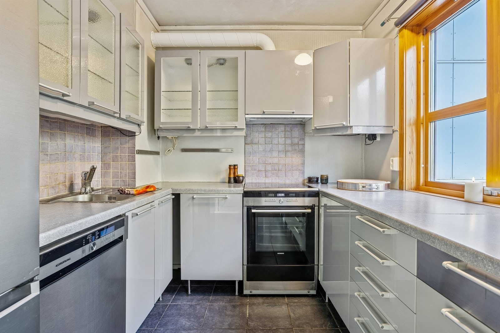 Kjøkkeninnredning med slette fronter og plass til stekeovn, platetopp, oppvaskmaskin og kombiskap. Galleribilde