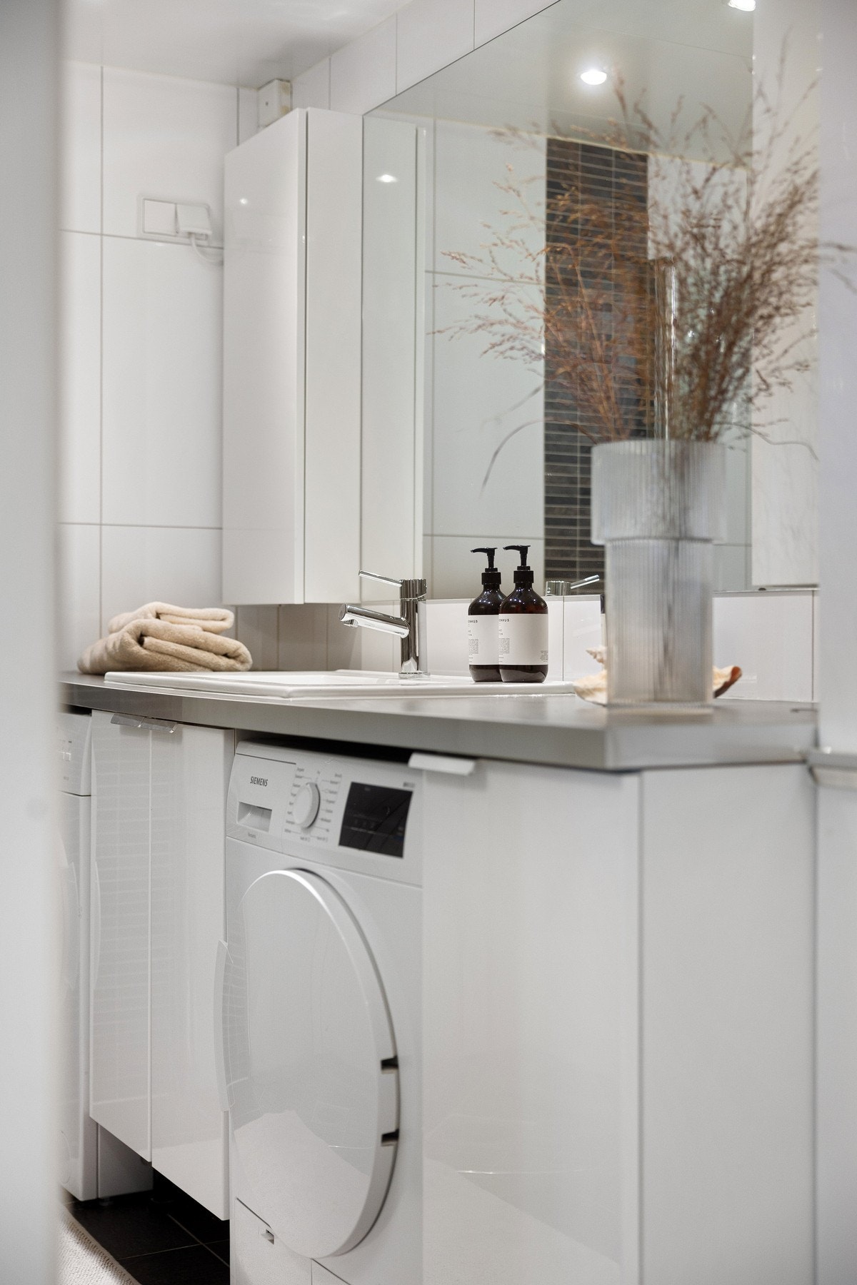 Smart innredning med mye oppbevaringsplass og nisjer for både vaskemaskin og tørketrommel under servantbenken. Galleribilde