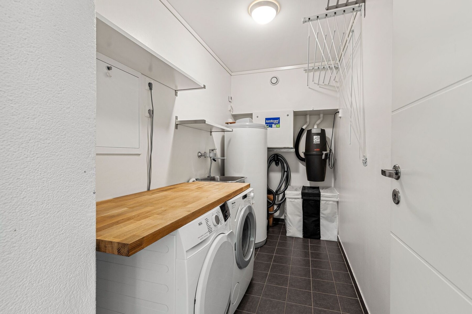 Vaskerom med rikelig med hylleplass og benkplass over vask/tørketrommel Galleribilde