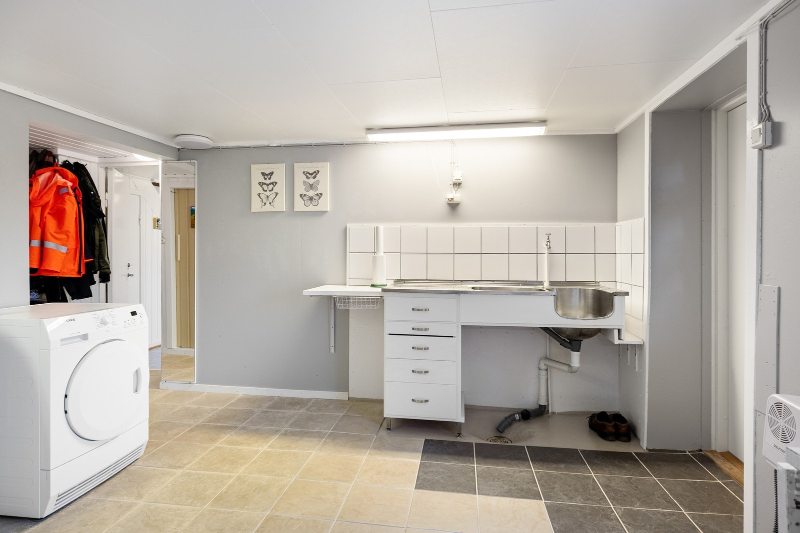 Innredning med benkeplate og utslagsvask. Gulvet er delvis flislagt og delvis av malt betong. Galleribilde