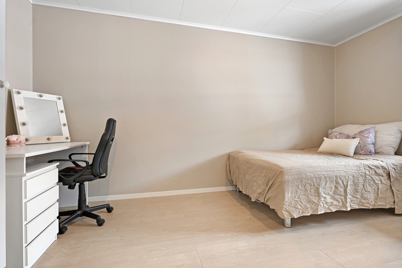 Rommet har lysmalte vegger og lyst gulv. Det er et skrivebord med skuffer og en kontorstol. Galleribilde