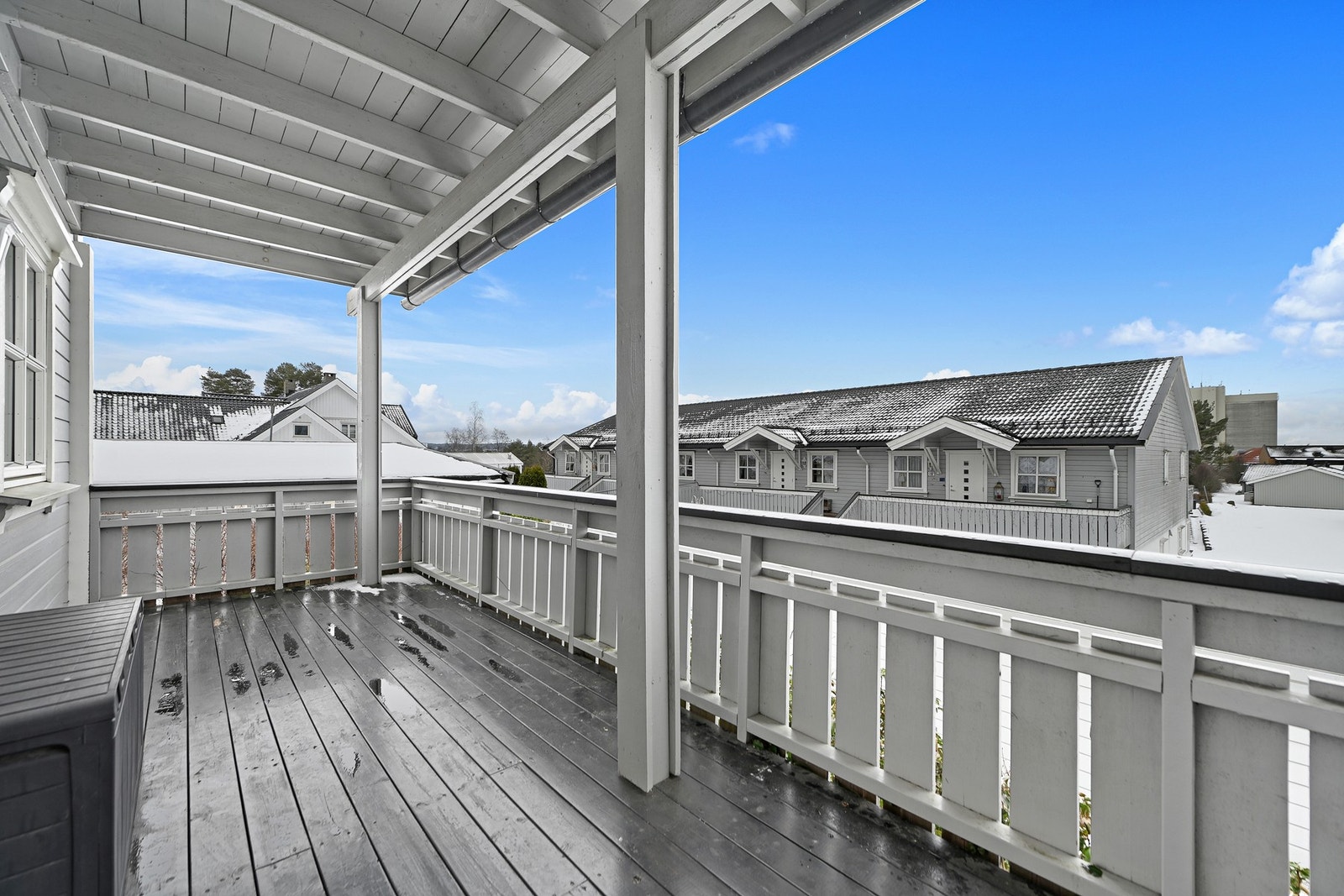 Balkongen har overbygg, rekkverk og utsikt mot nabolaget. Den gir mulighet for utendørs opphold i all slags vær. Galleribilde