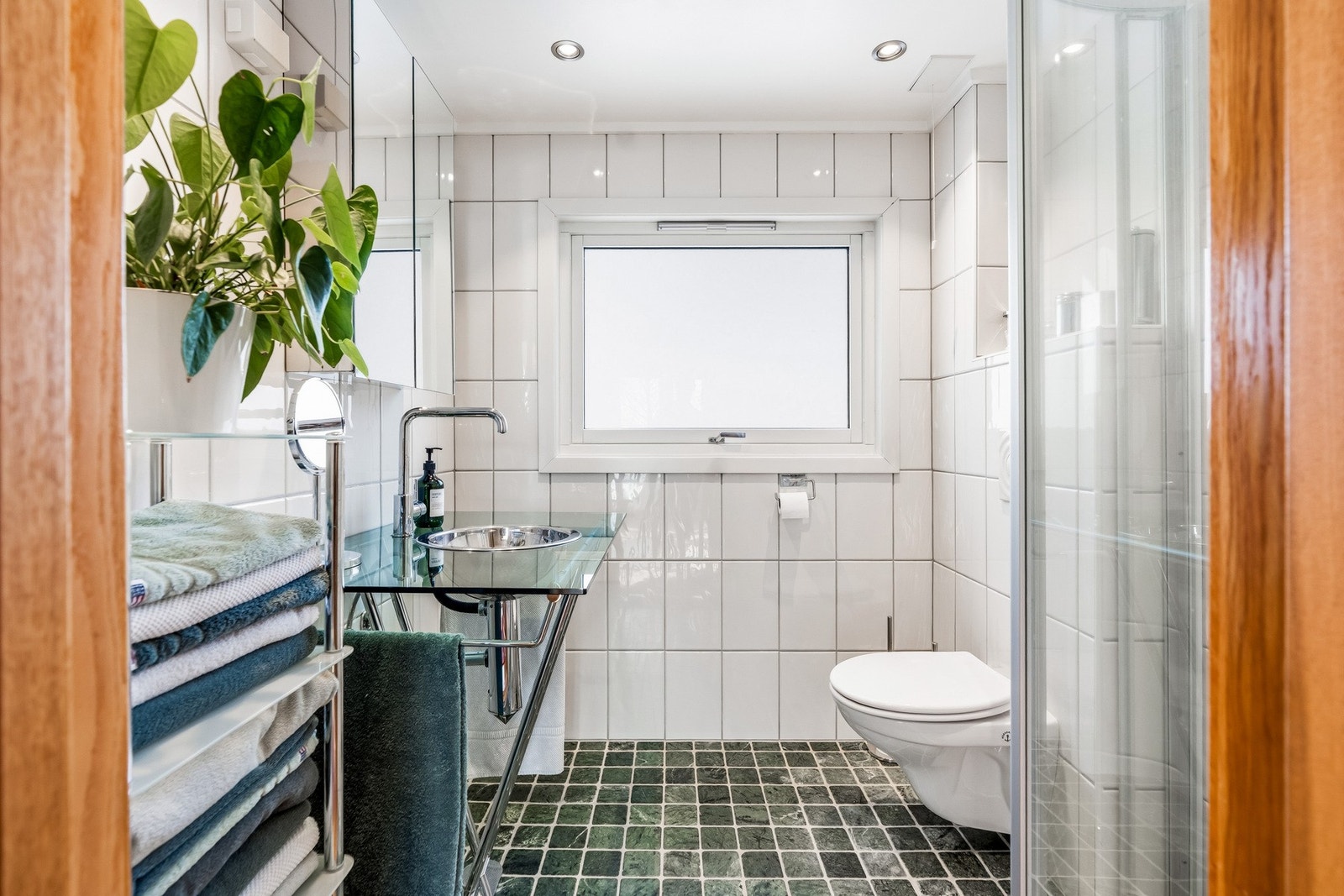 Badet i andre etasje er flislagt og har gulvvarme (1998). Belysning fra dimbare spotter. Innredningen består av baderomsinnredning med glassplate og nedsenket servantskål i metall, samt to vegghengte speilskap over servanten. Toalettet er veggmontert. Galleribilde