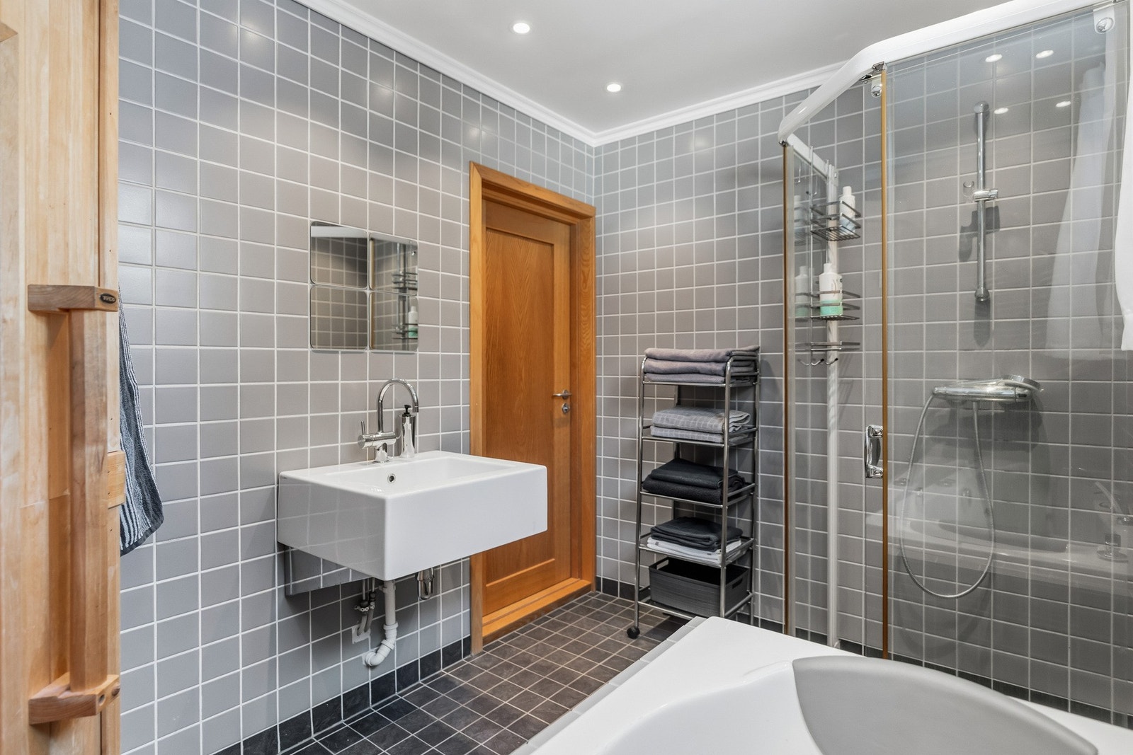 Innredningen består av vegghengt servant, dusjhjørne med skyvedører samt et innfliset badekar med dusj. I tillegg er det installert en badstumodul på badet. Ventilasjonen med elektrisk avtrekksvifte og tilluft via luftespalte i vindu og ventil i veggen. Galleribilde