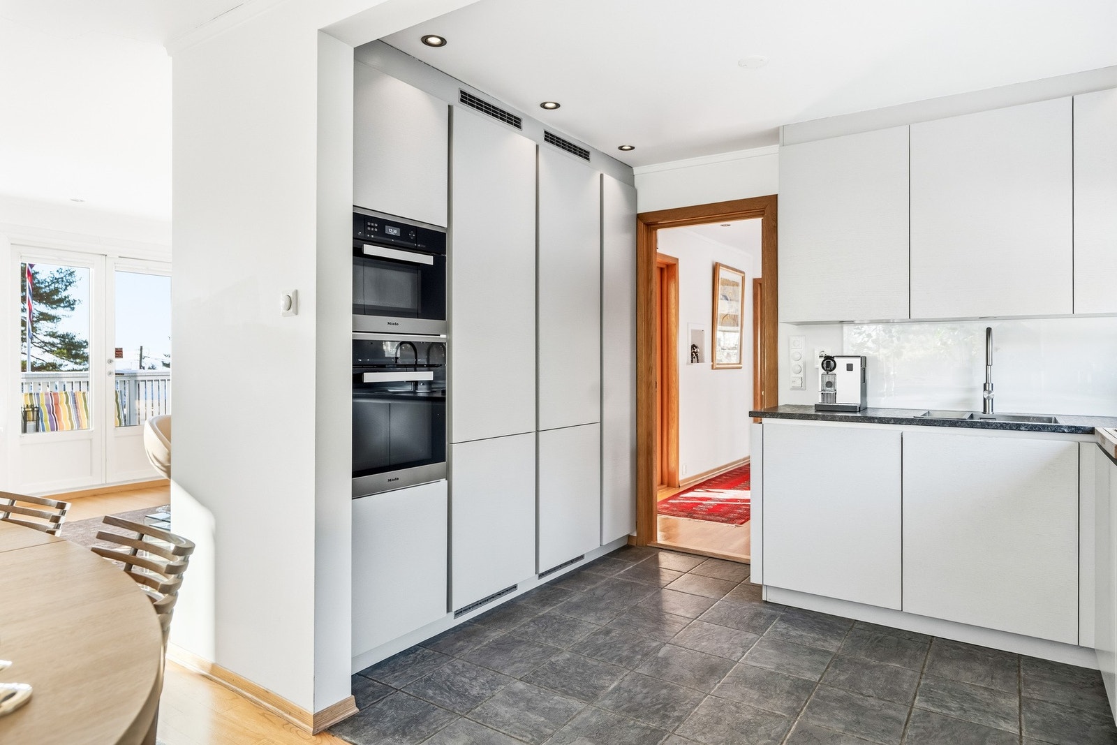 Integrert komfyr fra Miele, integrert dampovn fra Miele, induksjonstopp fra Miele med integrert ventilator, oppvaskmaskin, to kombiskap fra Miele, samt vannstoppesystem. Galleribilde