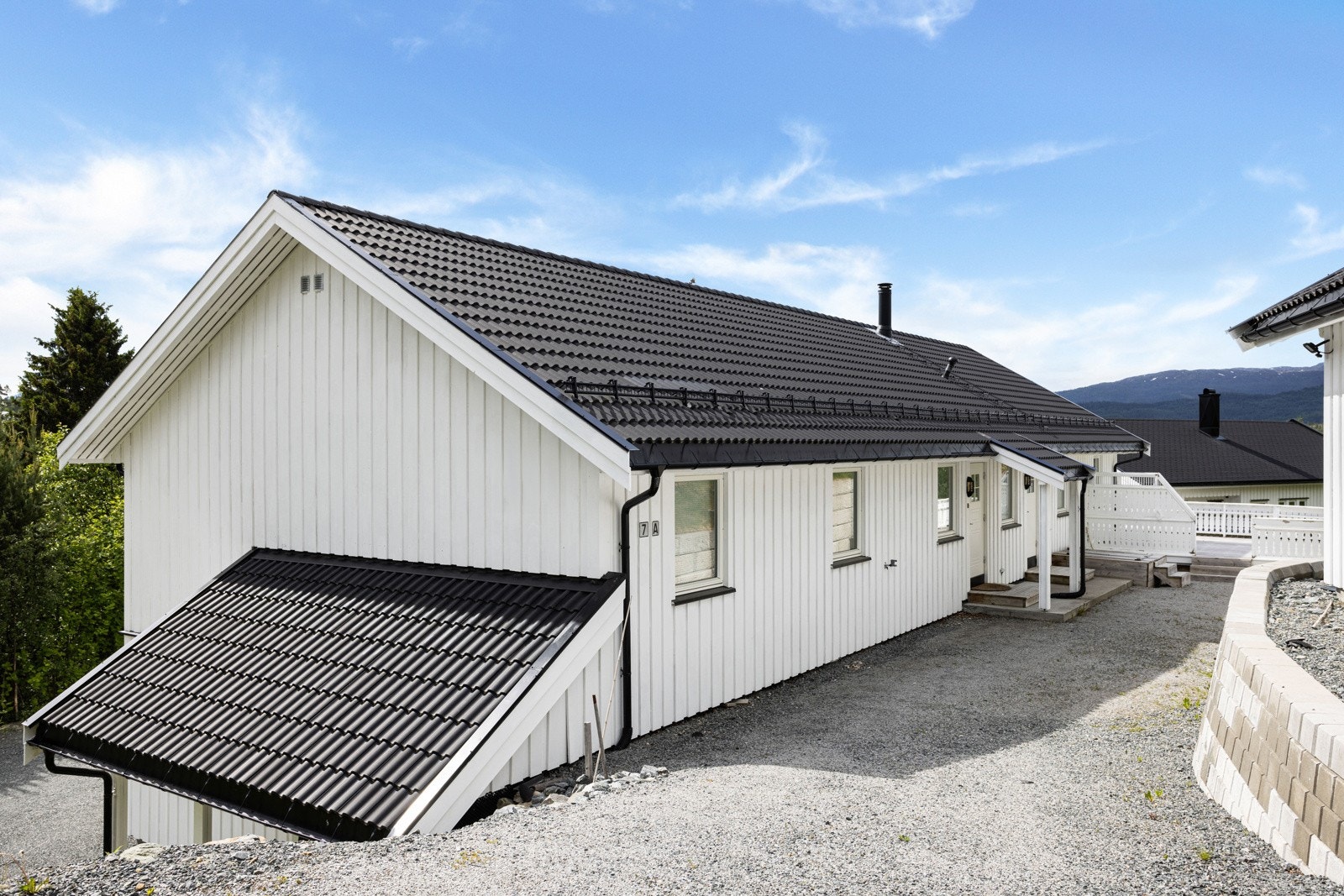 Gårdstun til hoveddelen. Tomten er pent opparbeidet med gruset tun, mur og veranda. Galleribilde