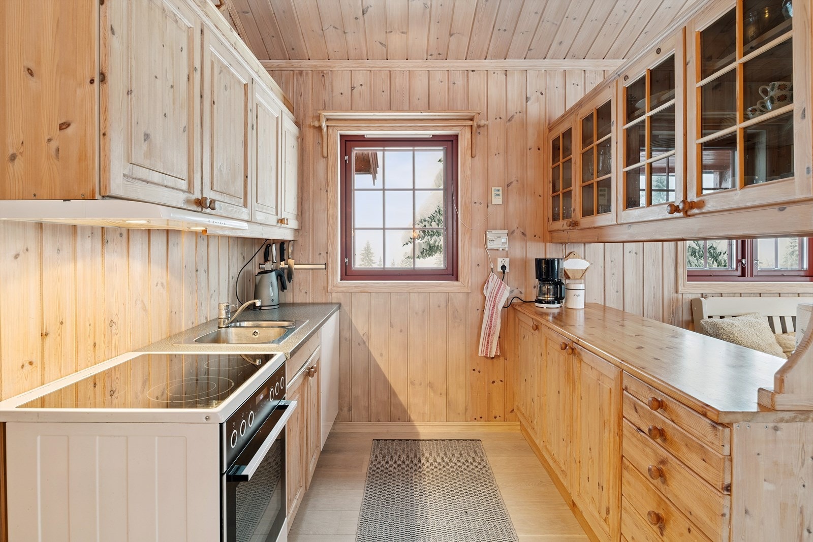 Kjøkkeninnredning fra byggeåret med trefronter, laminerte benkeplater og ventilator over komfyr. Galleribilde