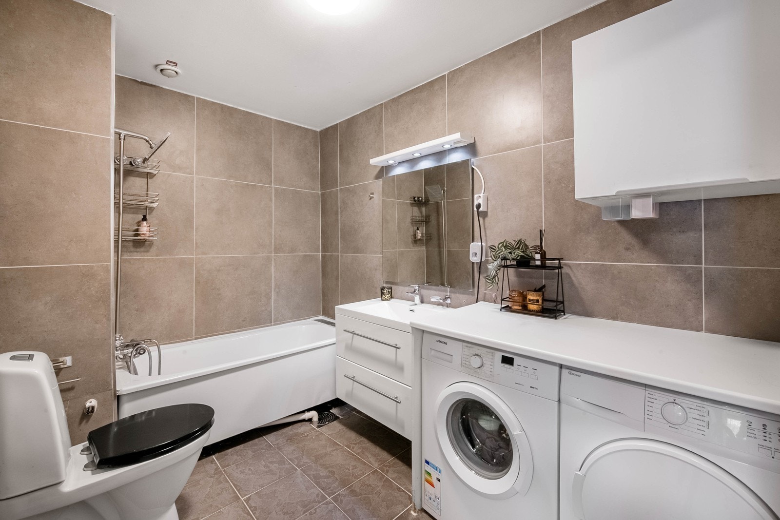 Baderom med fliser på gulv, plater på vegger. Opplegg vaskemaskin og trommel Galleribilde