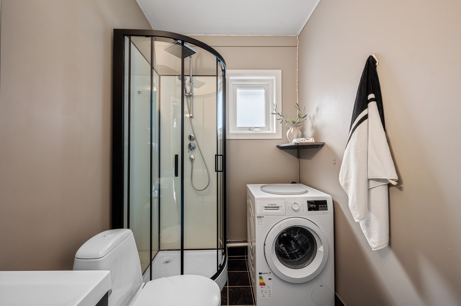 Praktisk innredet bad med dusjkabinett og opplegg for vaskemaskin. Galleribilde