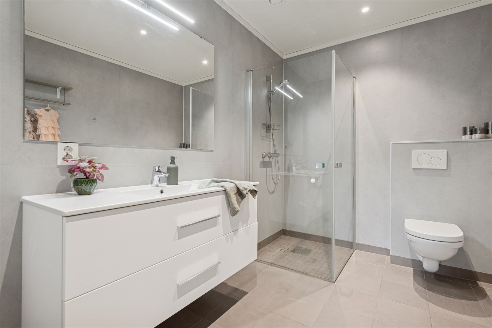 Pent bad utstyrt med dusjhjørne og vegghengt toalett. Galleribilde