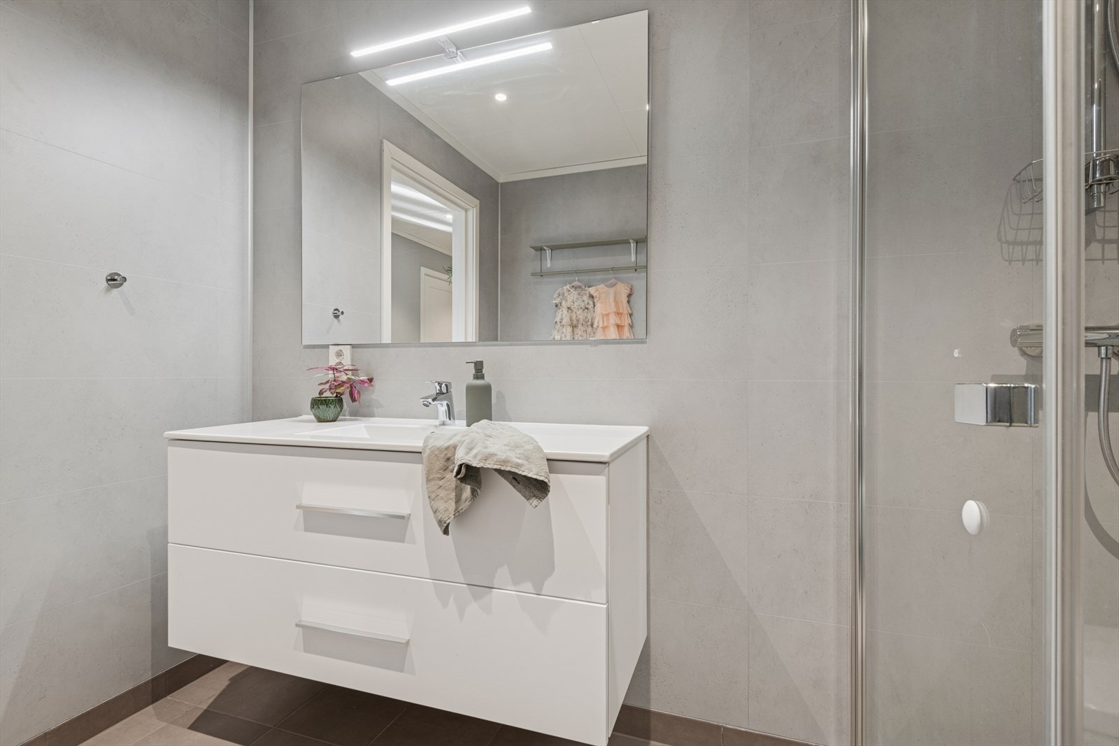 Lys og moderne baderomsinnredning med gode skuffer, servant og speil med belysning over. Galleribilde