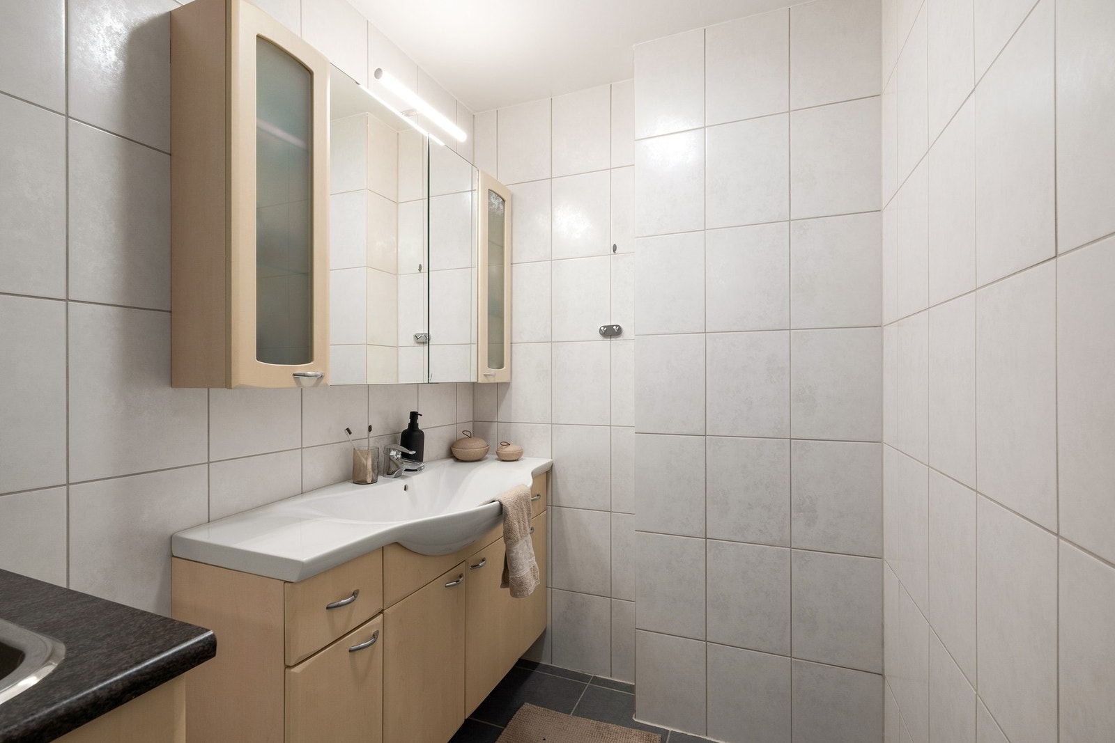 Badet er flislagt og har varmekabler i gulv, dusjløsning, vegghengt toalett og opplegg for vaskemaskin. Galleribilde