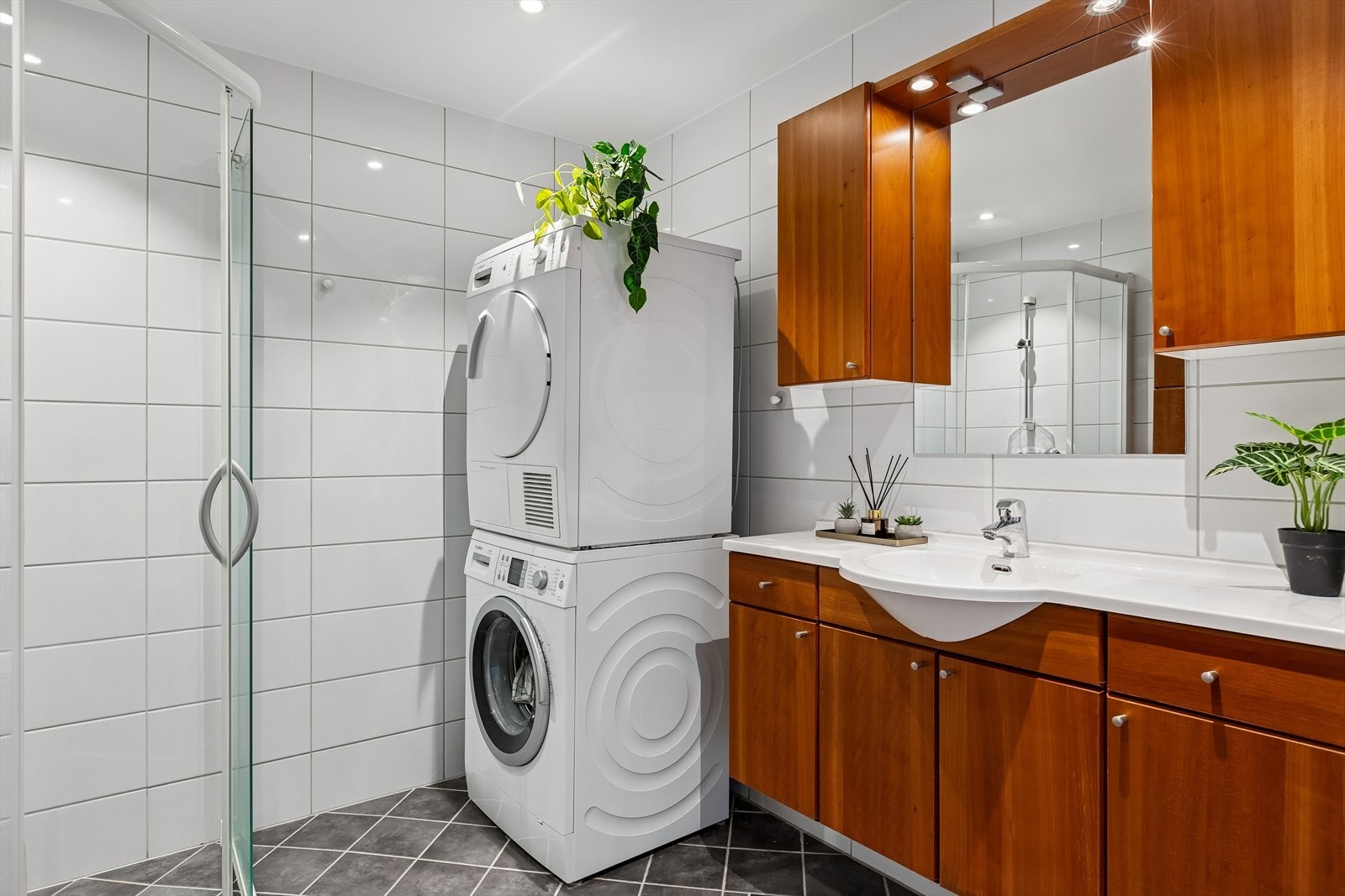 Flislagt bad utstyrt med servant, opplegg for vaskemaskin og dusjnisje. Galleribilde