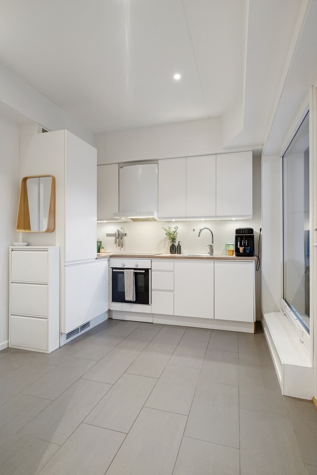 Når man trer inn, kommer man rett inn i kjøkkenet, et rom med fliselagt gulv med elektriske varmekabler og lyse vegger. Galleribilde