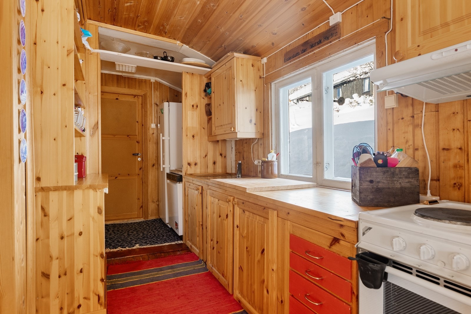 Inntil stua er det kjøkken med innredning på to sider og plass til det man måtte trenge på hytta. Vinduet på kjøkkenet gir godt arbeidslys til benkeplate med nedfelt oppvaskkum. Kjøkkenet har hvitevarer som oppvaskmaskin, komfyr og kjøl/fryseskap. Galleribilde