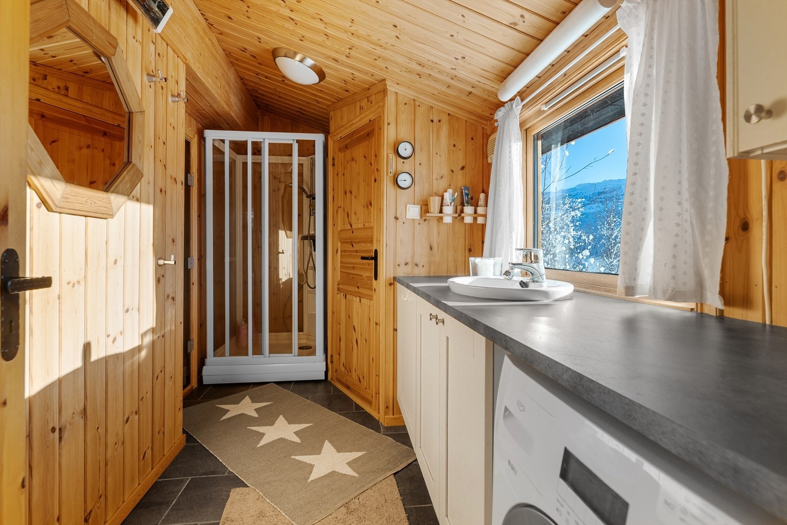 Badet i sanitærbygget har flislagt gulv med varmekabler som gjør det godt og varmt å komme inn her. Dusjkabinett og tilliggende toalett og badstue. Galleribilde