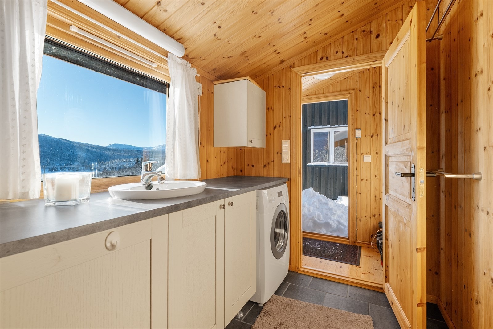 Badet er innredet med benkeplate med nedfelt servant og underskap, samt at vaskemaskinen har fått plass under benken. Galleribilde