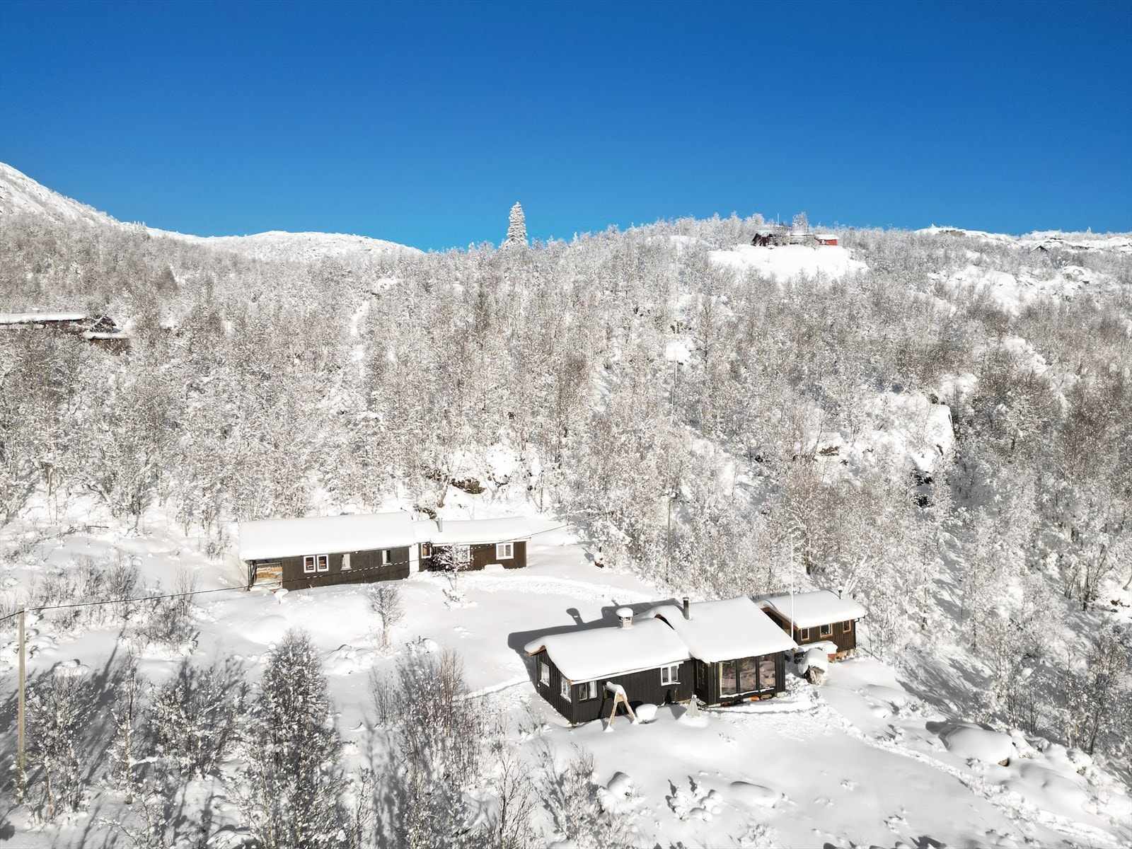 Koselig og sjarmerende hyttetun med fantastisk utsikt i naturskjønne omgivelser. Eiendommen består av to hytter med tilsammen 5 soverom og eget sanitærhus med bad og badstue. Alle bygningene har innlagt vann! Galleribilde