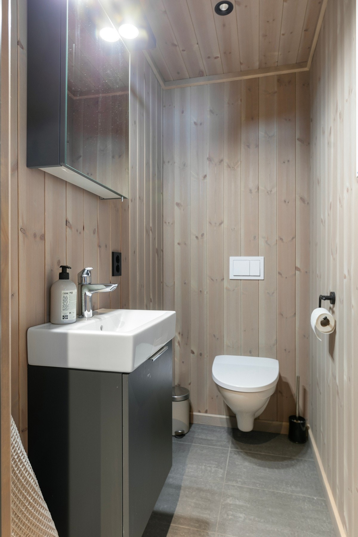 Toalettrom med panel på vegger og fliser på gulv. Galleribilde