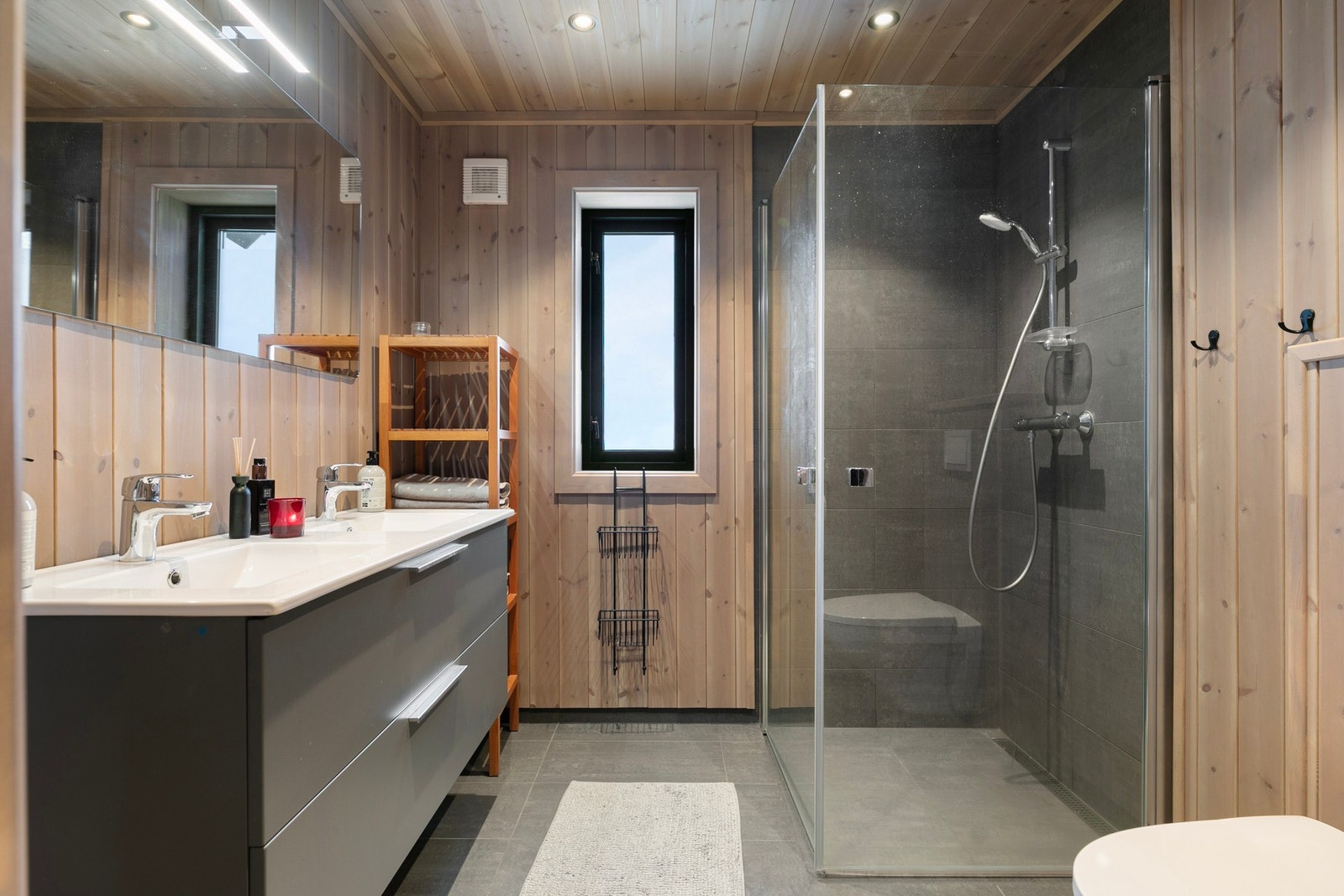 Bad med flislagt gulv med gulvvarme og panel og fliser på vegg. Galleribilde