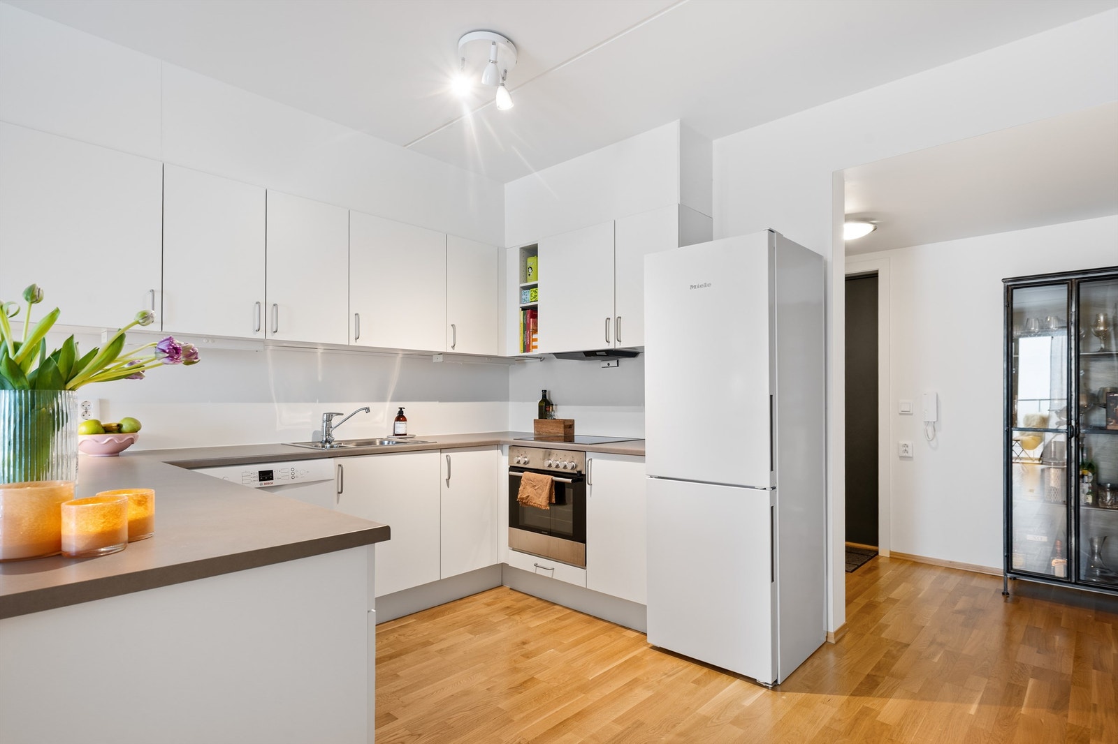 Kjøkkeninnredning med glatte fronter og laminert benkeplate, overskapsbelysning og stikkontakter Galleribilde