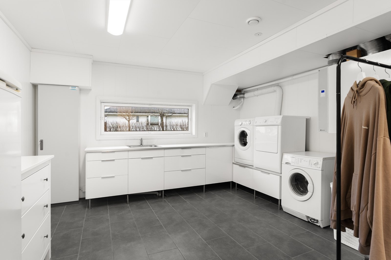 Romslig vaskerom med seksjonert innredning og utslagsvask - godt tilrettelagt for en effektiv hverdag. Galleribilde