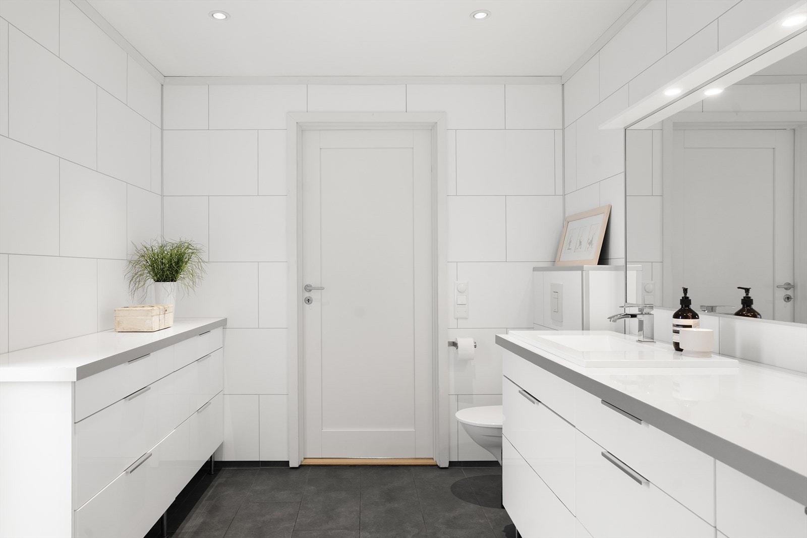 Badet er innredet med vask i seksjon, vegghengt toalett og plassbygd dusj. Galleribilde