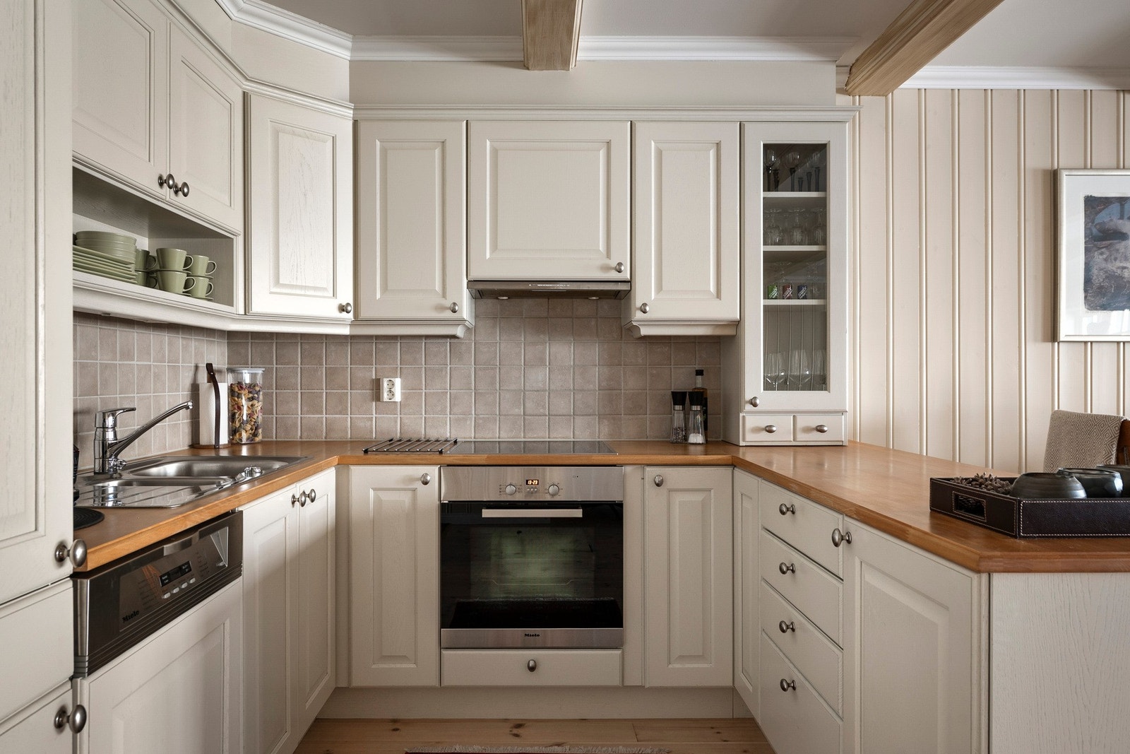 Benkeplate i tre og nedfelt oppvaskkum. Kjøkkenet er godt utstyrt med integrerte hvitevarer: stekeovn, platetopp, oppvaskmaskin samt kjøleskap med fryser. Ventilator er plassert i overskap. Galleribilde