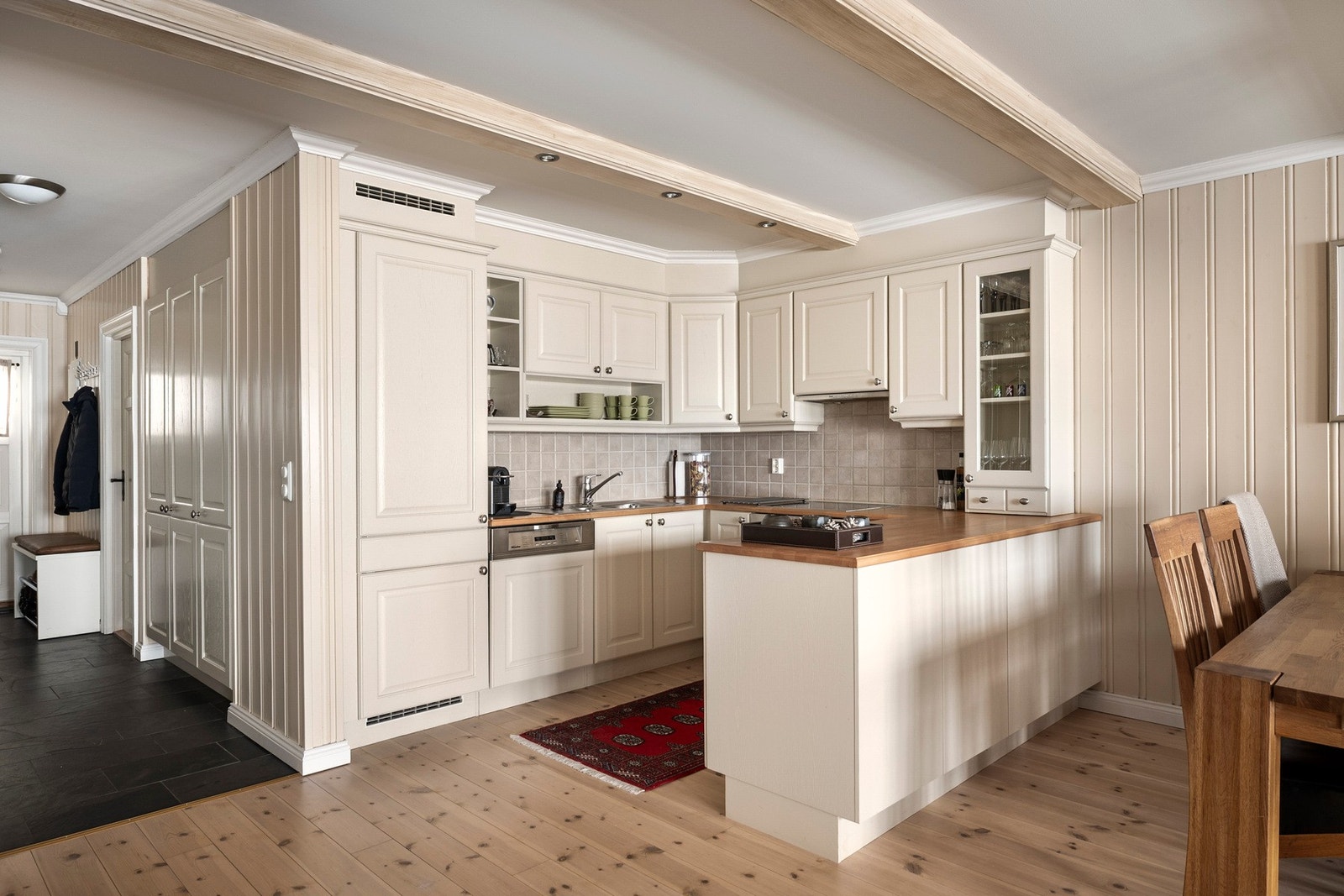 Åpen kjøkkenløsning med innredning i klassisk stil og profilerte fronter. Galleribilde