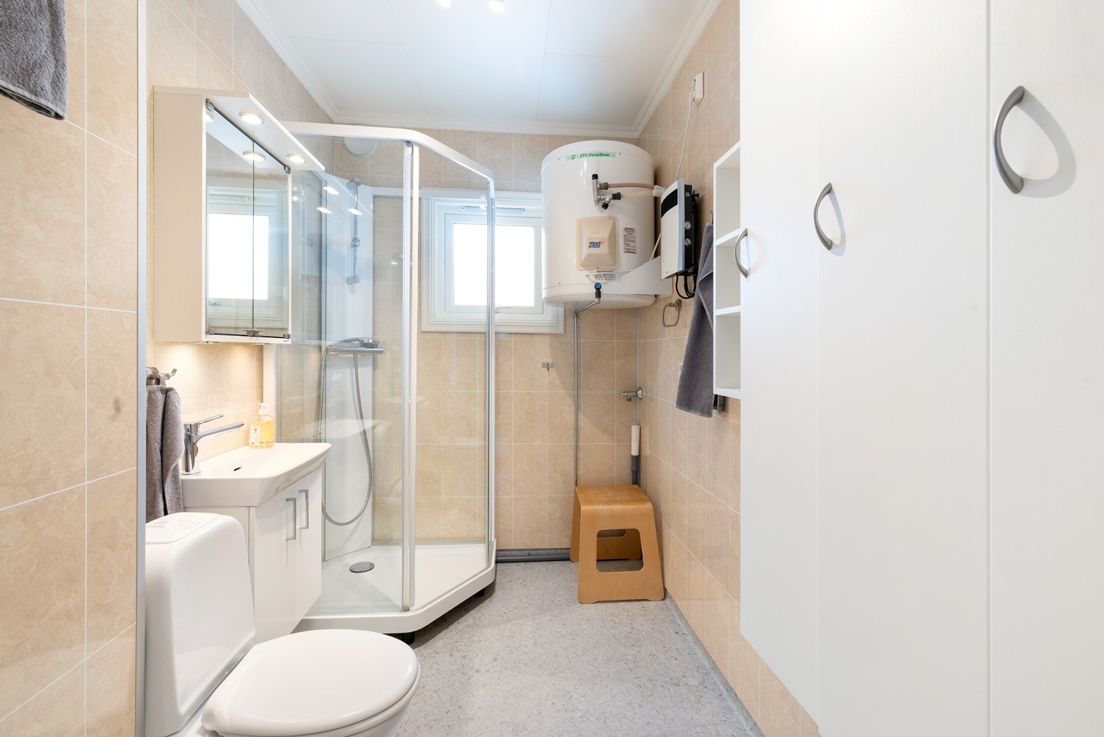 Badet har wc, servant med skap, dusjkabinett og opplegg vaskemaskin Galleribilde