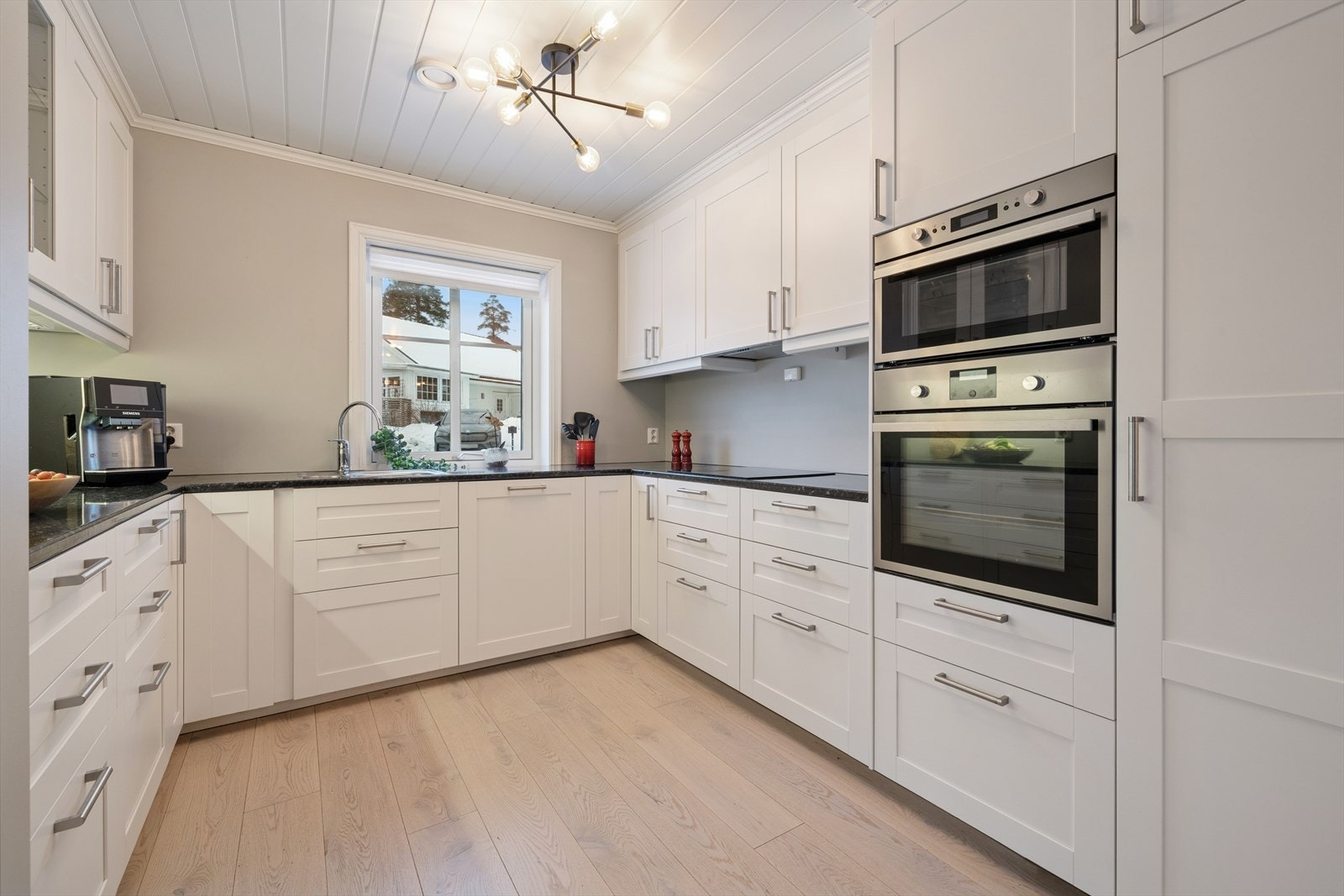 Det er godt med skapplass, og et av overskapene har dekorative glassdører. Kjøkkenet er utstyrt med hvitevarer som induksjonstopp, stekeovn, mikrobølgeovn, oppvaskmaskin og kjøleskap. Galleribilde