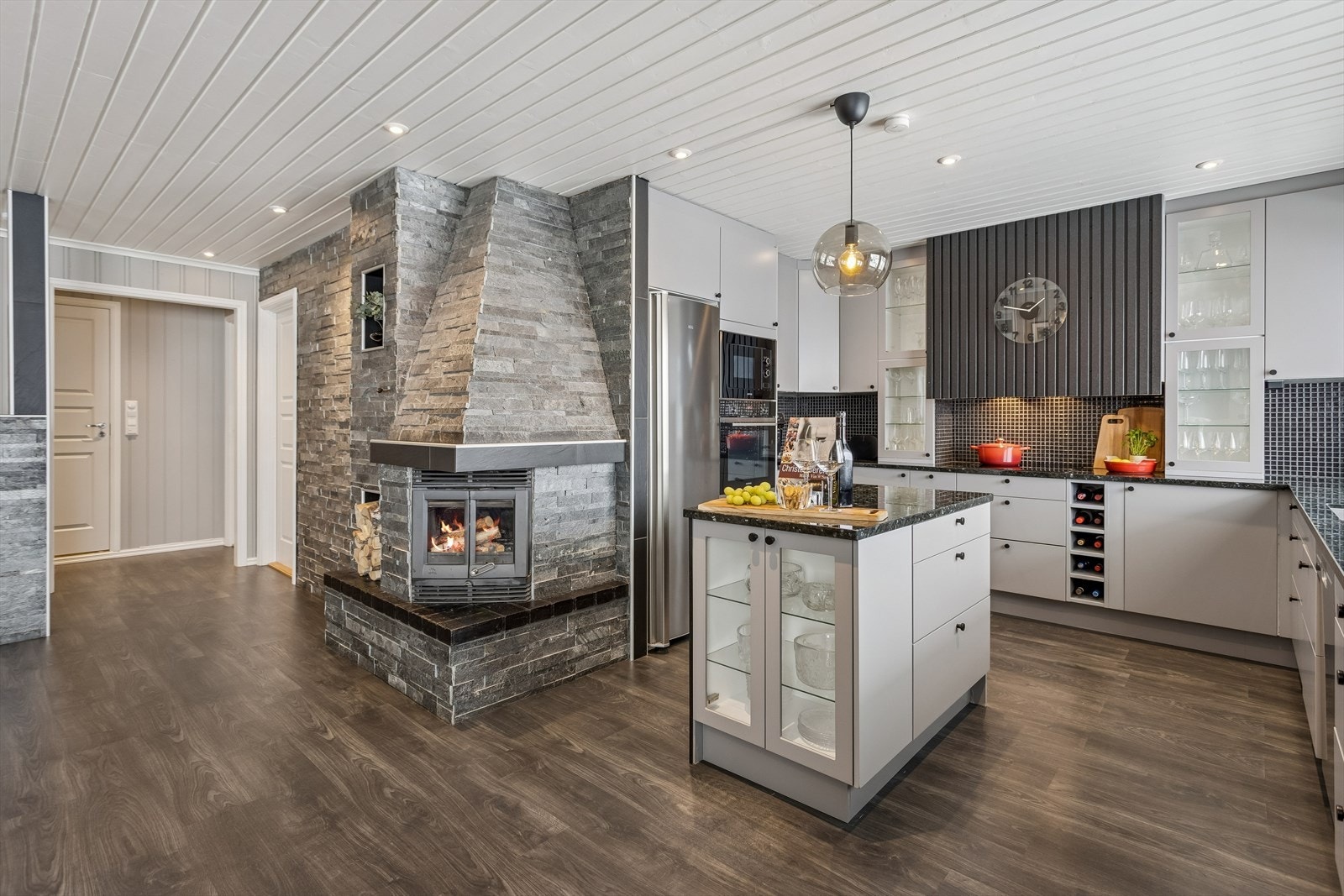 Den lukkede peisen er et sentralt element mellom kjøkken og stue, og gir god varme. Galleribilde