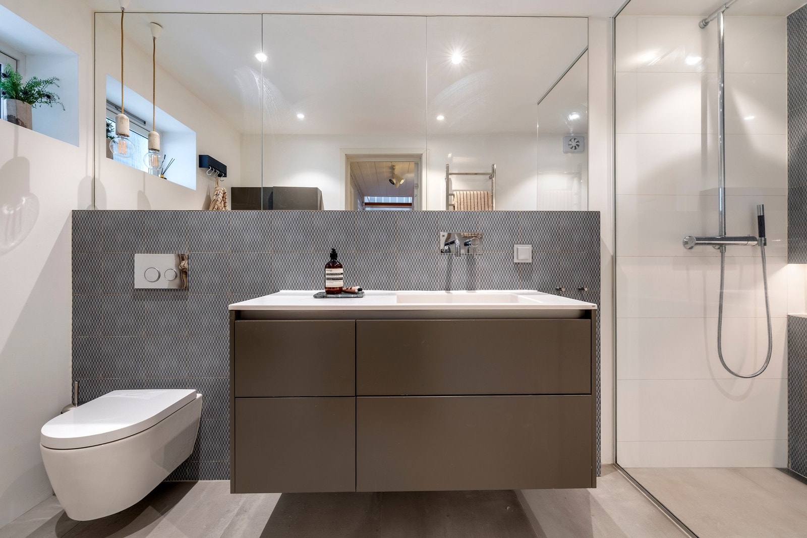 Badet har downlights, malte vegger som er kombinert med flislagte vegger i dusjsonen, samt flislagt gulv med varmekabler. Galleribilde