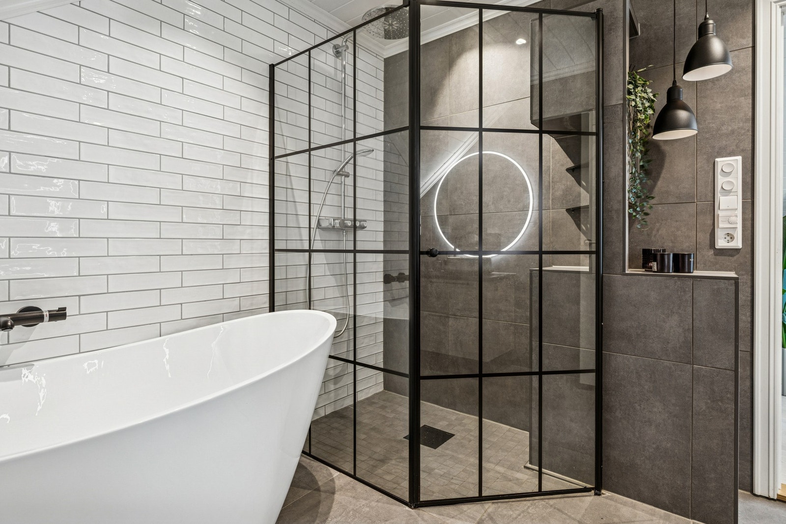 Videre er badet utstyrt med både frittstående badekar, romslig dusjsone med glassdører, vegghengt toalett og en elegant servantinnredning. Galleribilde