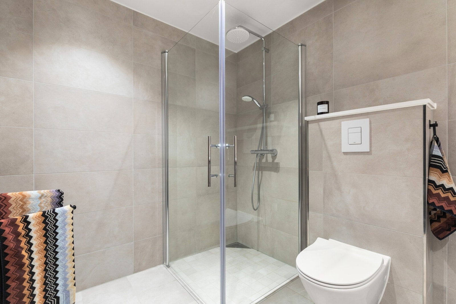 Badet er utstyrt med dusj, servantseksjon med skuffer og vask, innmurt speil, stikkontakter, vegghengt wc og opplegg for vaskemaskin/tørketrommel. Galleribilde