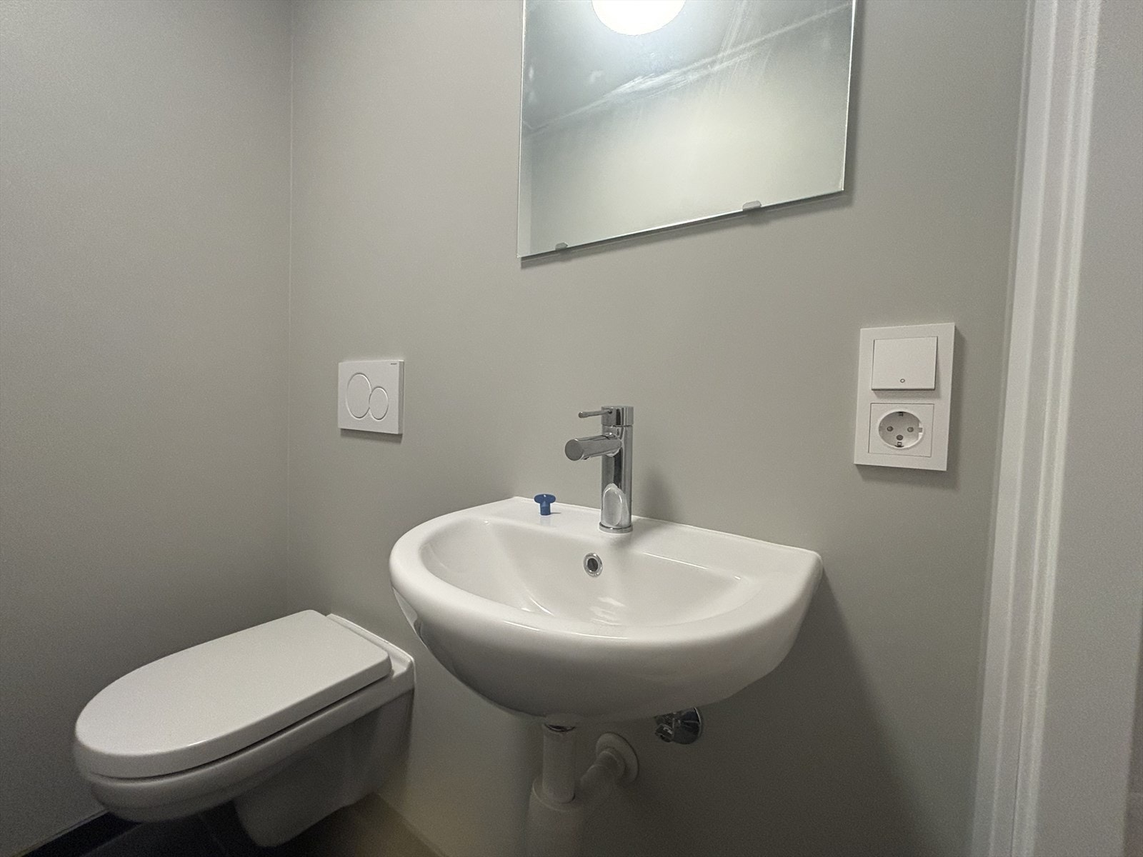 Toalettrom med vegghengt wc og servant. Flislagt gulv. Galleribilde