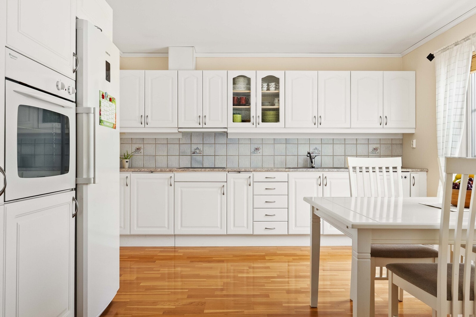 Kjøkkeninnredningen er plassert langs veggene i en funksjonell løsning som gir gode arbeidsflater og effektiv flyt i hverdagen. Galleribilde