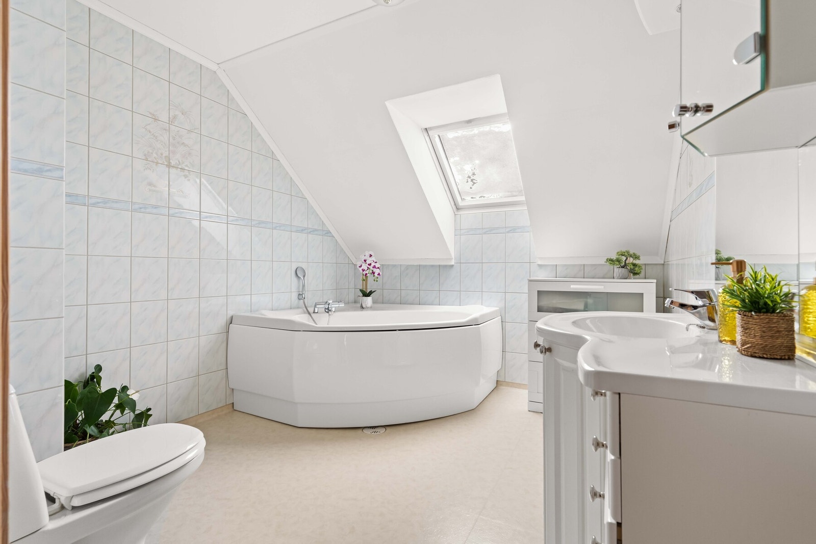 Badet med badekar plassert under takvindu som slipper inn behagelig dagslys. Galleribilde