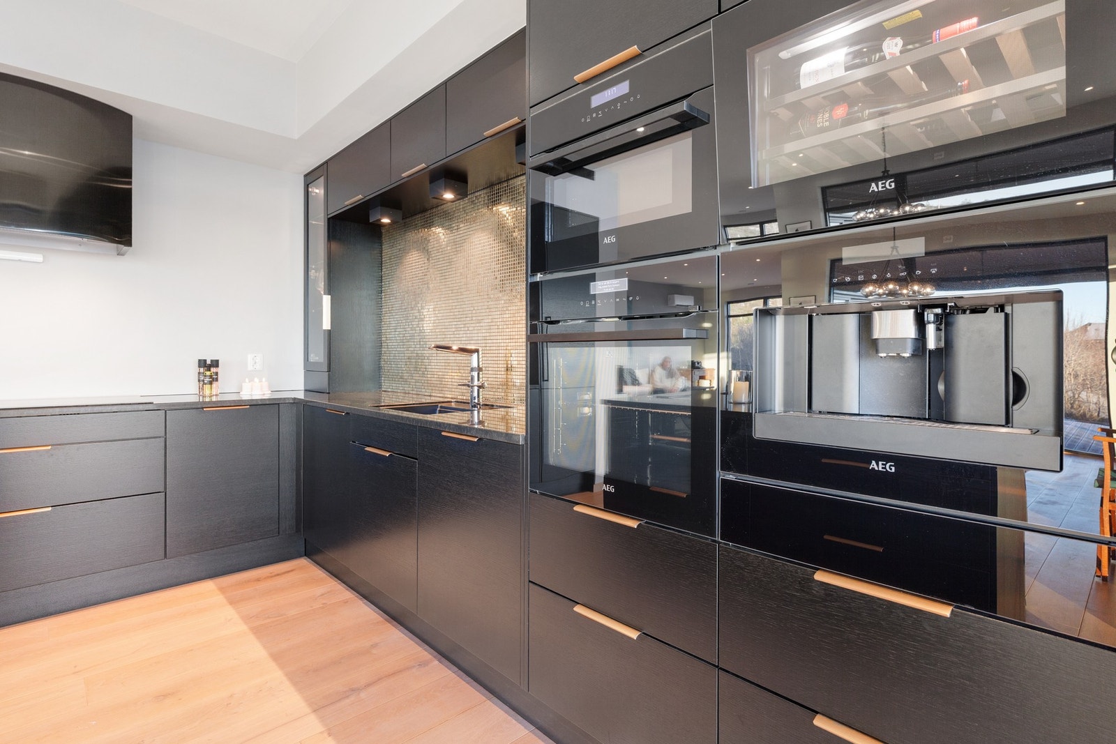 Kjøkkenet har integrerte hvitevarer fra AEG som stekeovn, micro, kaffemaskin, vinskap, varmeskuffe, oppvaskmaskin, platetopp og kombi kjøle/fryseskap Galleribilde