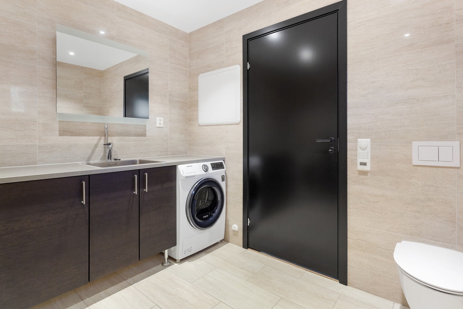 Bad/vaskerom: Rommet innehar vegghengt toalett, dusjgarnityr på vegg og vaskeromsinnredning med nedfelt vask og opplegg for vaskemaskin. Galleribilde