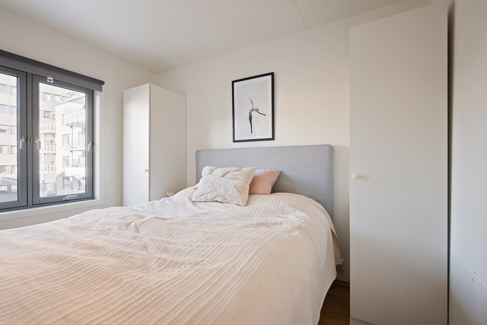 Rommet har plass til dobbeltseng, og på hver side av sengeplassen er det frittstående, enkle garderobeskap i hvitt. Galleribilde